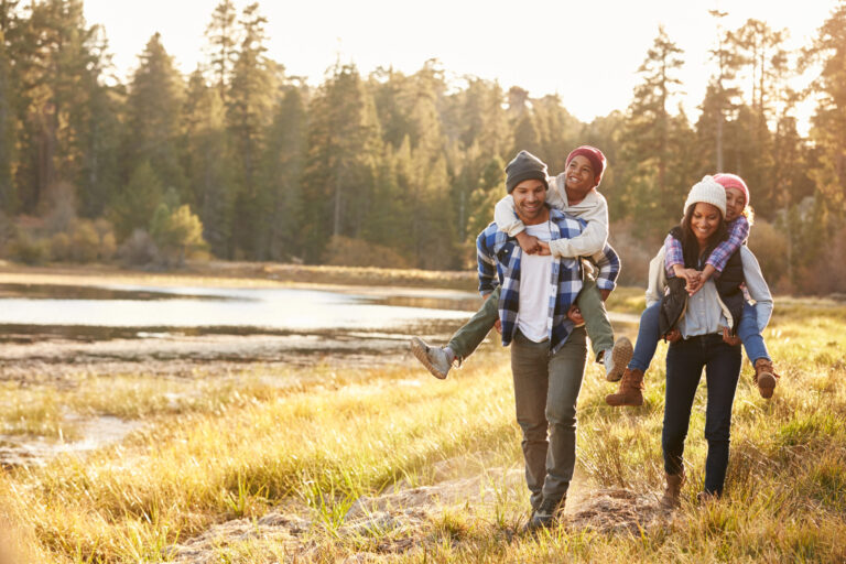 Parents,Giving,Children,Piggyback,Ride,On,Walk,By,Lake